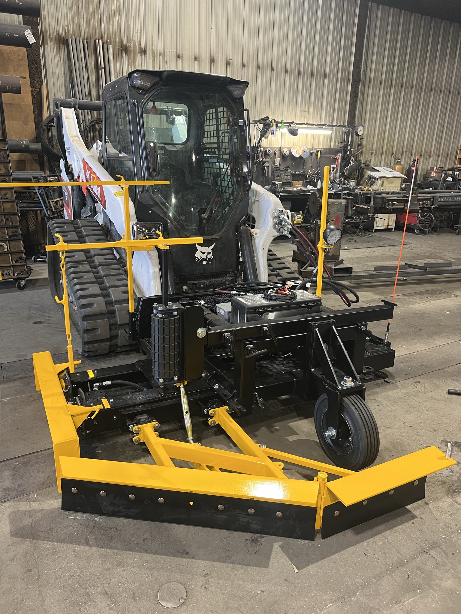 Custom yellow and black skid steer attachment with angled blade, built in the Allwayz shop